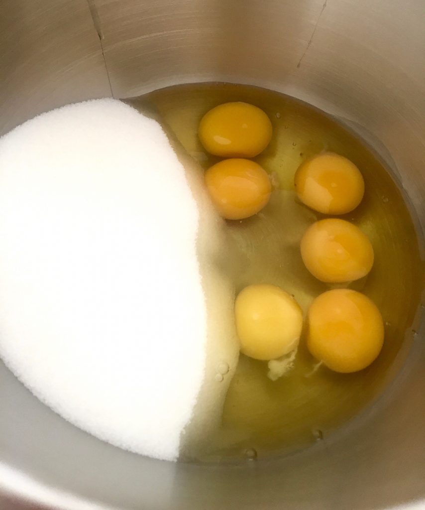 6 Eier und Zucker liegen in einer Rührschüssel vorbereitet.